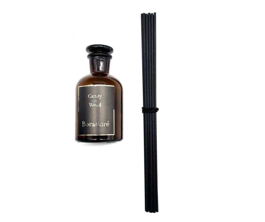 Boradoré Candy Wood reed diffuser in amber glass bottle on white background
