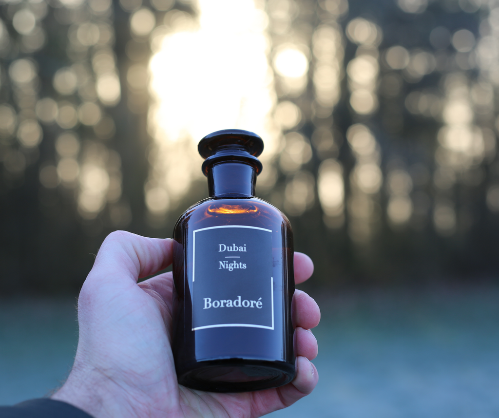 Boradoré Dubai Nights perfume bottle held in hand against a softly blurred natural background
