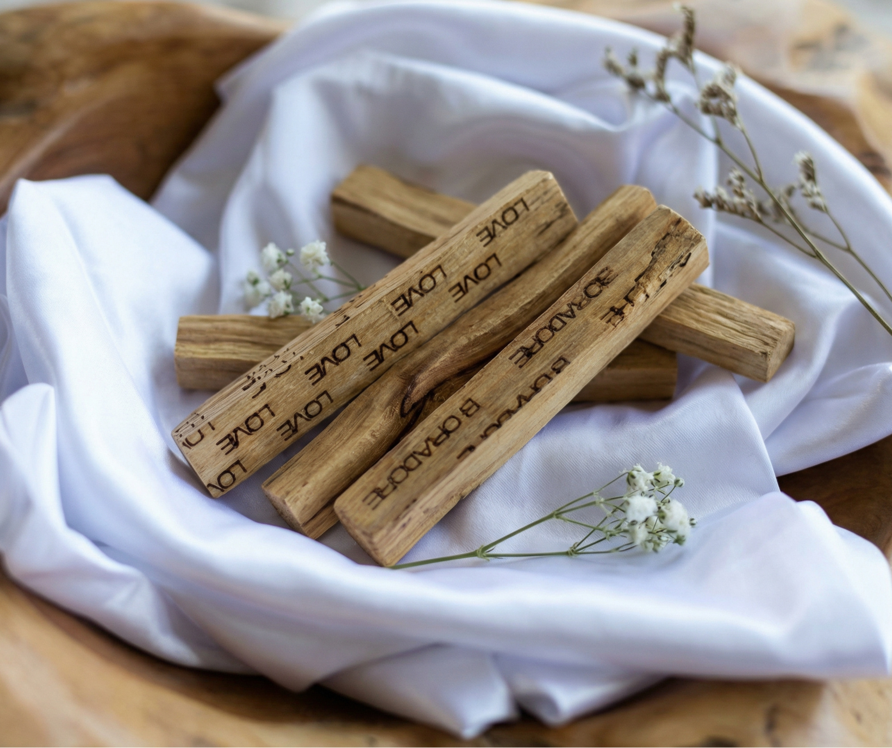 Boradoré palo santo wood sticks arranged on white fabric with dried flowers
