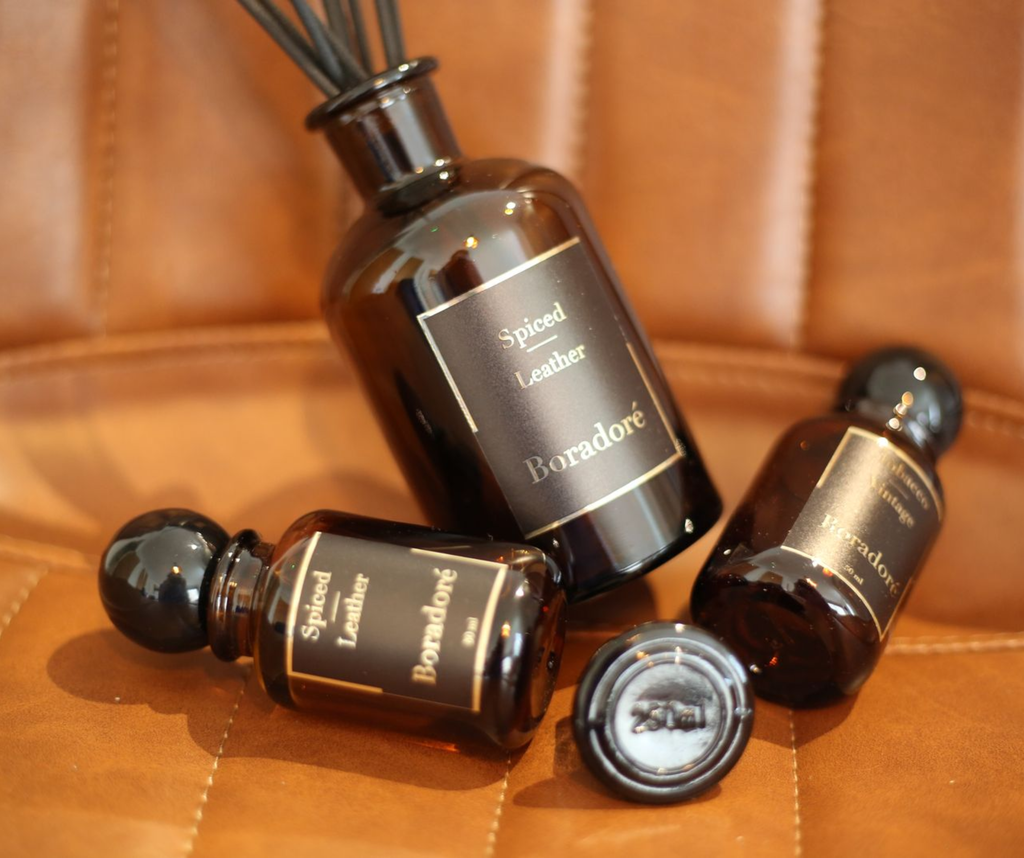 Boradoré Spiced Leather reed diffuser bottles on a brown leather surface
