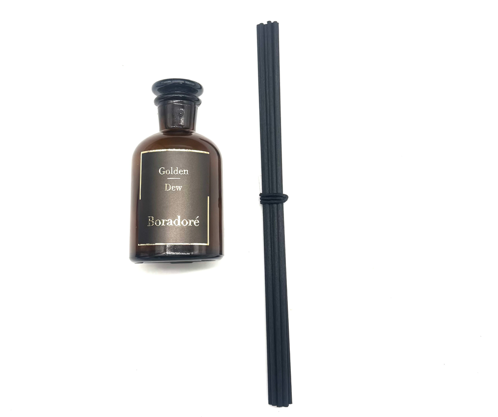 Boradoré Golden Dew reed diffuser in amber glass bottle on white background
